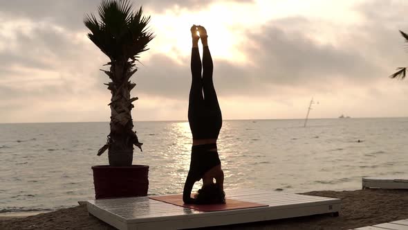 Woman Standing on Head in Yoga Pose Salamba Shirshasana Outdoor Practicing Yoga Asana on the Beach alt