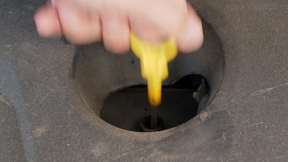Close-up of checking the oil level on the yellow knob oil dipstick in a used car alt