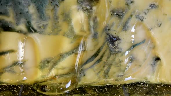 Drops of honey flowing down from the Dorblu cheese on a mirrored black background. alt