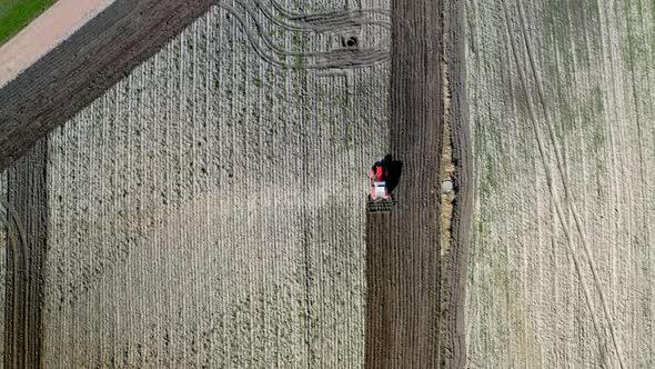 Red tractor plowing field, aerial view in spring alt
