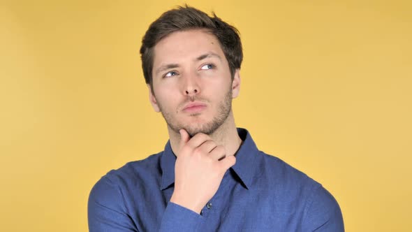 Pensive Casual Young Man Got New Idea on Yellow Background alt