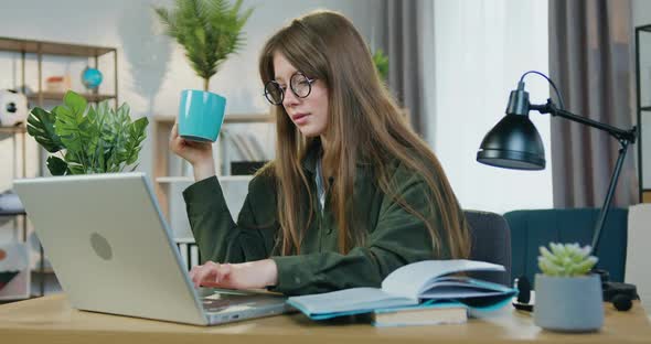 Female Student in Glasses Sitting at Home and Working Over University Home Task on Computer alt