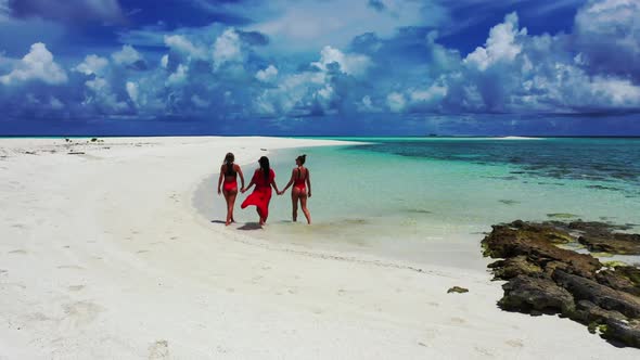 Beautiful women relaxing on idyllic lagoon beach voyage by shallow water and bright sandy background alt