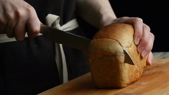 A Woman Cutting a Loaf of Bread with a Bread Knife. Slow Motion