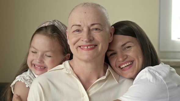 An Adult Daughter and Little Granddaughter Hug a Sad Elderly Woman Who Has Gone Bald After alt