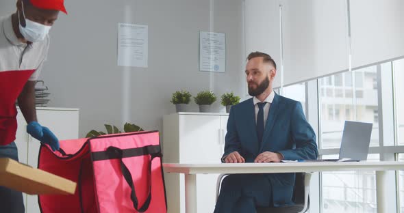 Delivery Man in Medical Face Mask and Gloves Giving Pizza Boxes Tamale Customer at Office alt