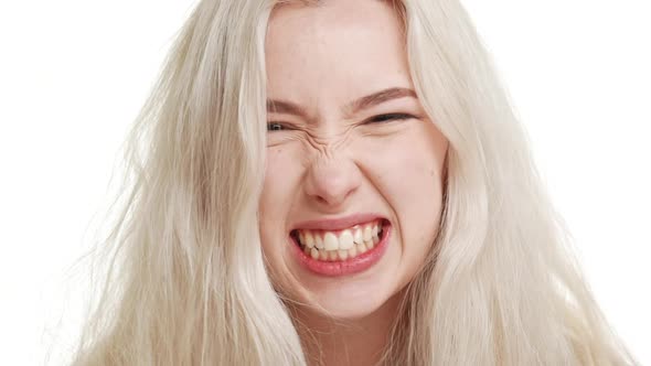 Angry Blonde Caucasian Teenage Girl Fixedly Looking Grimacing on White Background in Slowmotion alt