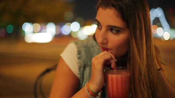 Teenage girl enjoying drink outdoors at night