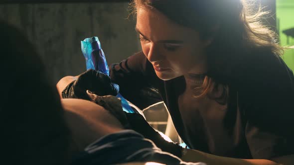 Closeup of Tattooer Woman Working with Naked Clients Body Ink Dye Painting