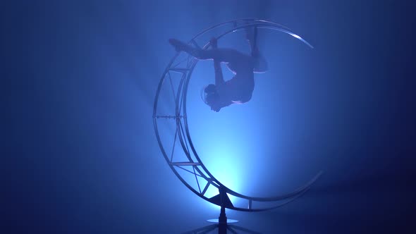 Gymnast in a Brilliant Costume Performs Tricks on a Special Design Moon alt