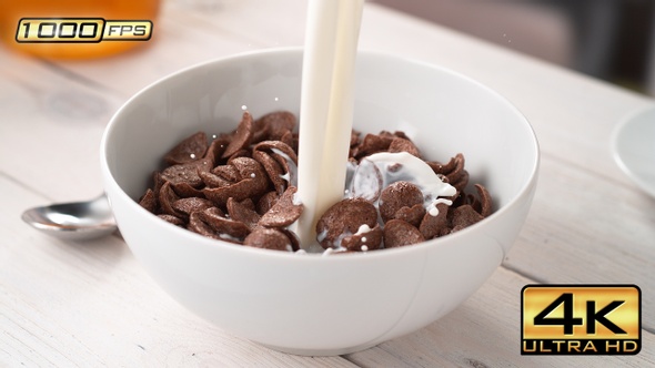 Pouring Milk into Bowl with Cocoa Shell-Shaped Cereals alt