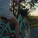 Side view of unrecognizable caucasian woman riding a bike on sunset on village road. Shot with RED h - VideoHive Item for Sale