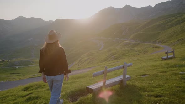Travel  woman in hat in lights of a sun walks and sits on bench against mountain landscape alt