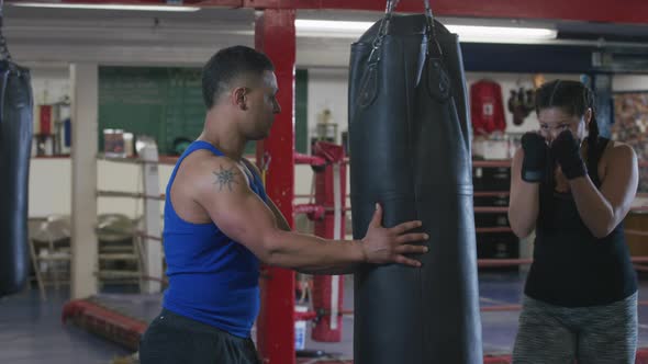 Woman and trainer working out at boxing gym