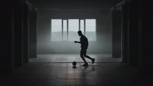 The Silhouette of a Football Player Training in an Underground Parking Lot in the Sun and Rising alt