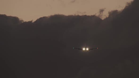 Plane with Headlights Ascending Against Heavy Clouds in Evening Sky alt