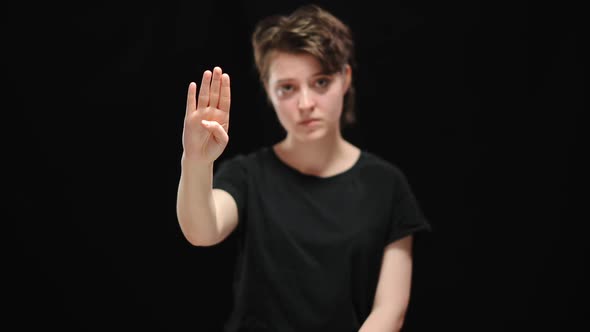 Palm at Camera with Tuck Thumb and Blurred Sad Woman at Black Background alt