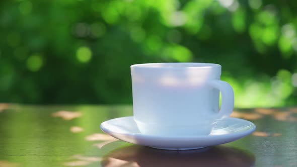 Hot Drink in a Cup Against the Background of a Summer Garden in the Morning alt