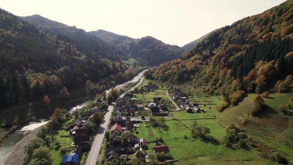 Aerial View of a Mountain Village Along the River in the Middle of a Sunny Summer Day alt