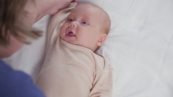Grandma Does Hands Gymnastics with Newborn Girl on Bed alt
