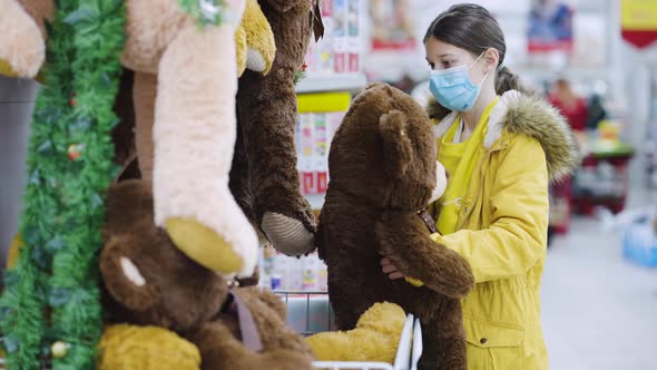 Girl hugging teddy bear in toy department alt