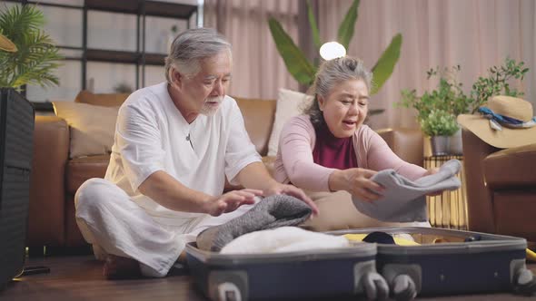 old asian senior couple packing cloth and stuff for a trip together