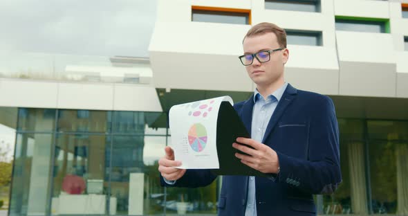 A Businessman is Looking Through Working Documents alt