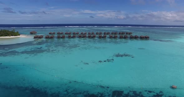 Aerial view of tropical island in Maldives. Overwater villas on turquoise water of Indian Ocean