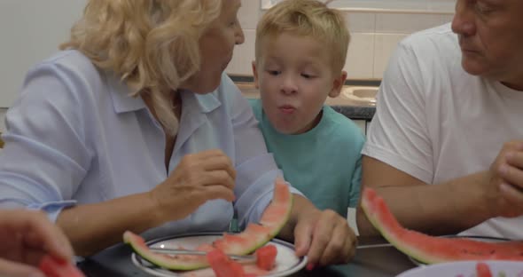 Grandma feeding grandchild with sweet watermelon alt