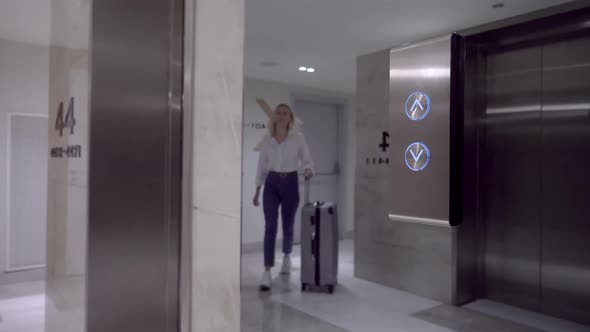 woman approaches elevator door and presses elevator call button with her finger.