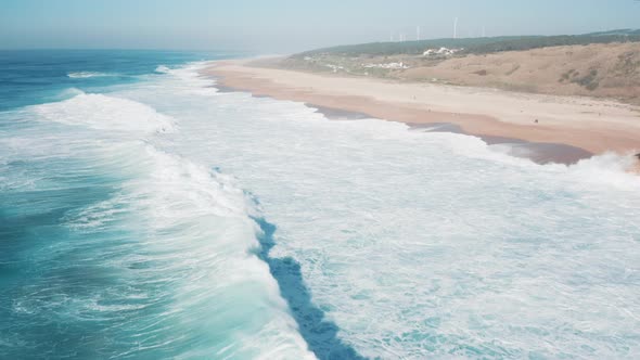 Aerial view of portuguese beach with rolling waves and bright sky