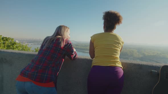 Rear View of Pretty Diverse Women Enjoying Cityscape at Sunrise alt