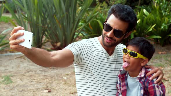 Father and son taking selfie with mobile phone alt