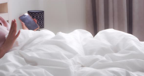 Woman Listens to Music Through Headphones and Dances Lying in Bed