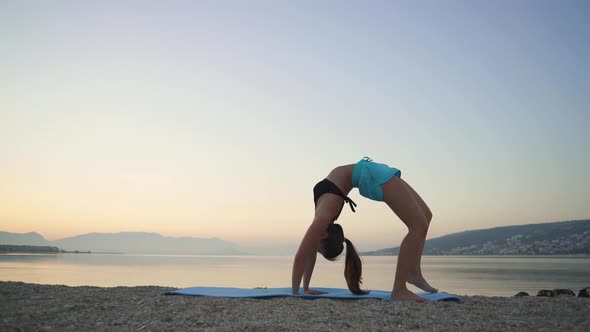 Beautiful Girl Warms Up and Practices Yoga By the Sea. Sports, Yoga, Beach.