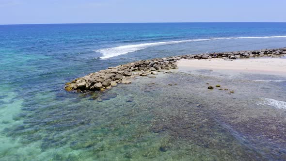 Rocky breakwater on Caribbean shoreline to prevent beach erosion alt