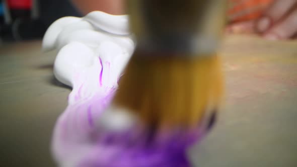 Closeup Shot of Artist Holding Paint Brush and Mix Color on Wooden Palette alt