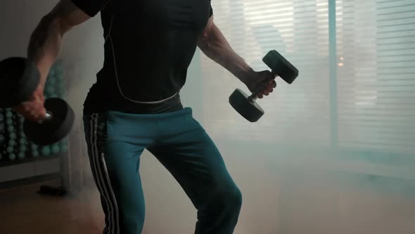 Muscled Sporty Man Working on Biceps with Huge Layout Heavy Dumbbells in Gym alt