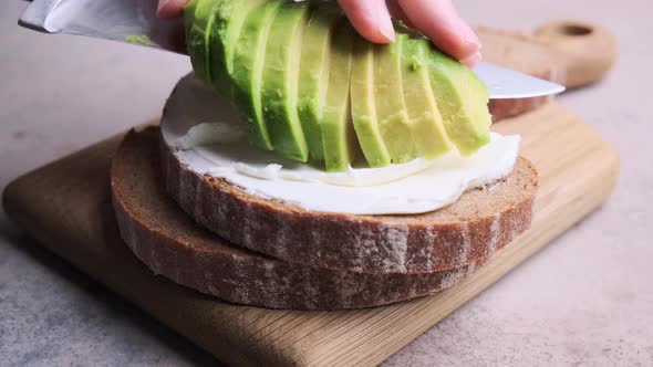 Cooking toast with avocado and cream cheese for breakfast. alt