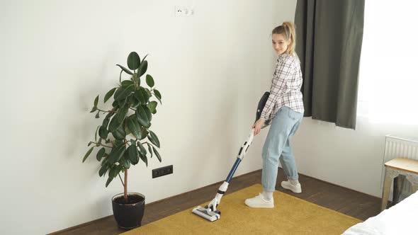 Caucasian Young Woman Wearing Casual Clothes Cleaning House Floor in Living Room Using Modern Vacuum