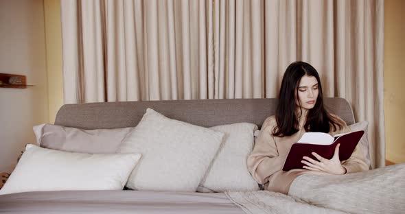 Woman Reading a Book Lying on Bed at Home alt