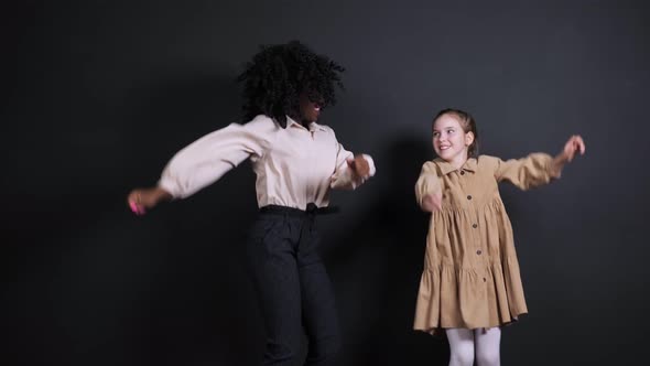Funny Black Dancing Woman Teacher Jumps with Young Lady alt