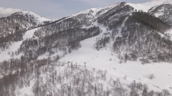 Flying over rope-way with gondolas at mountain resort Crystal Park in Bakuriani. Snowy winter day. alt