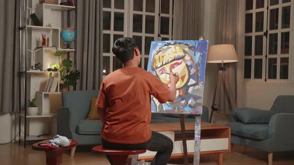 Asian Artist Boy Holding Paintbrush Mixed Colour And Thinking Before Painting A Girl's On The Canvas alt