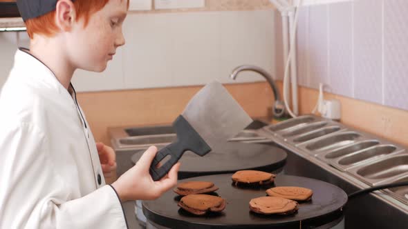 Boy Cooks Pancakes on an Industrial Professional Pancake Maker Kitchen in Cafe Little Chef