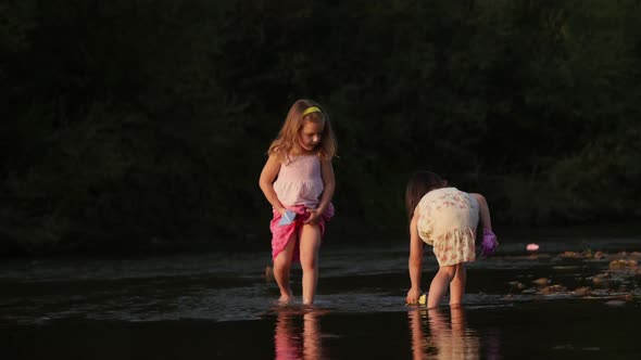 Two girls playing with paper boats alt