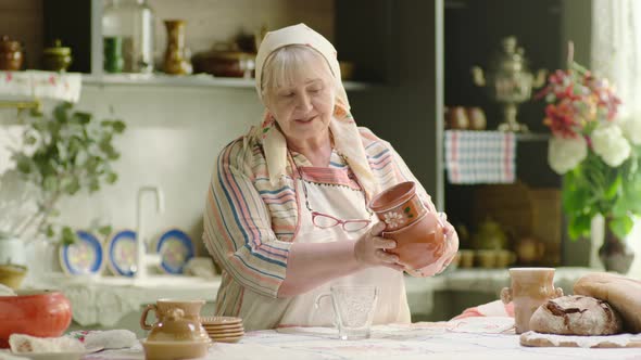 Grandmother Pouring Milk Into the Glass From Crock in the Country alt