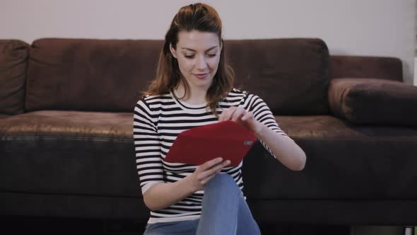 Young adult female opening Valentine's Day Card at home