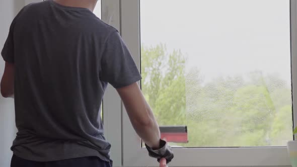 Man washes the windows with special foam and cleans them. Cleaning service. Worker in black gloves alt