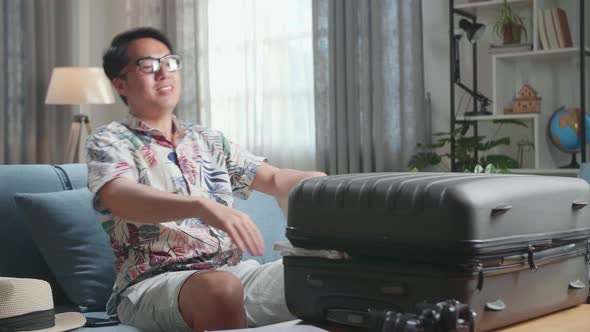 Asian Man Preparing For Travel Adventure, Packing Clothes Into Suitcase, Getting Ready For Road Trip alt